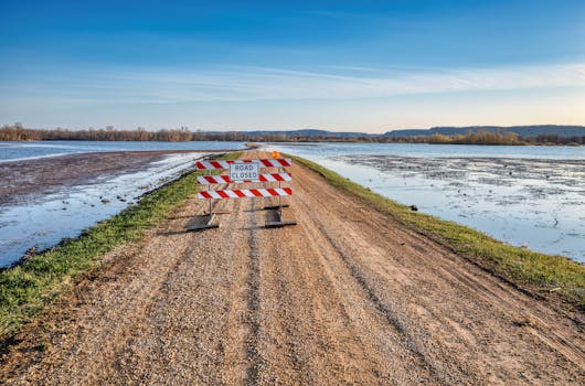 A road closed sign on a gravel path next to a flooded area in Kellogg, MN.