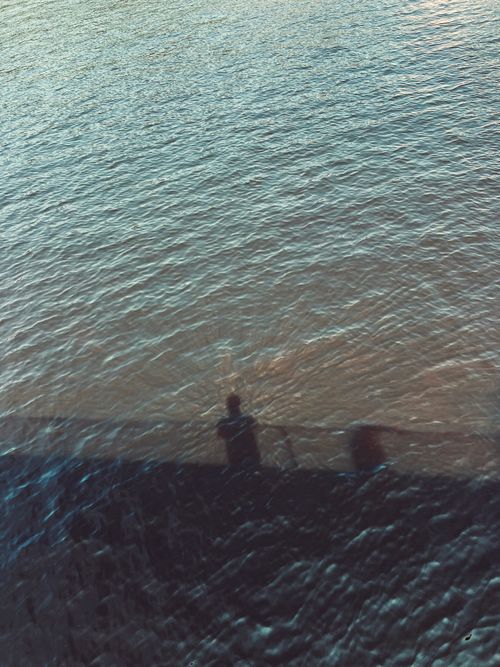 Free Shadow of a person reflected on rippling water, creating a serene and mysterious scene. Stock Photo