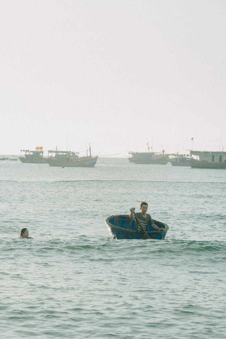 Man On Boat And Woman Swimming Near