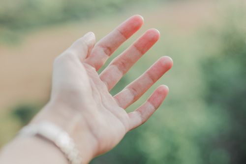 Free A close-up of an outstretched hand in soft focus with a blurred natural background. Stock Photo