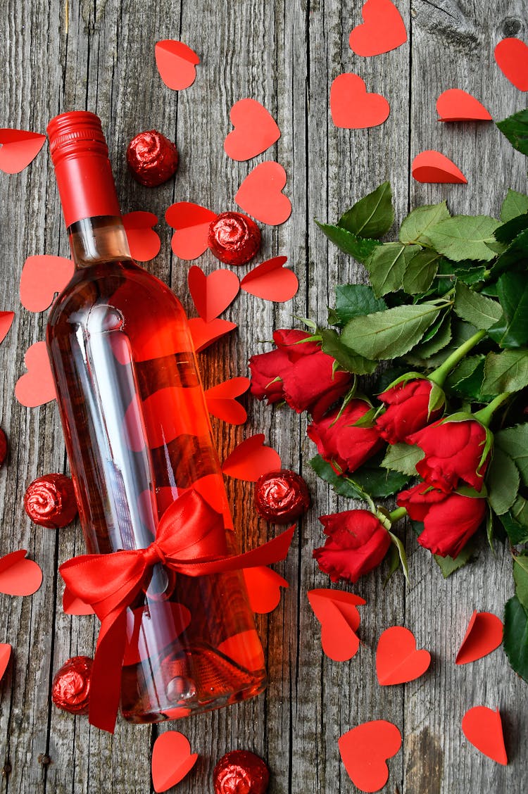 Flatlay Photography Of Glass Bottle And Bunch Of Red Rose Flowers