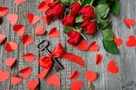 这是一个浪漫的场景：红玫瑰、心形切口，还有一把钥匙，用缎带绑在质朴的木头上