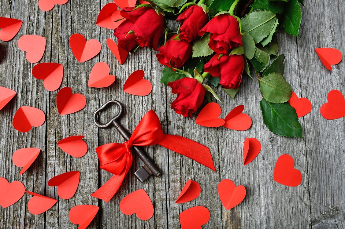 Black Metal Skeleton Key Beside Red Roses Bouquet on Gray Surface