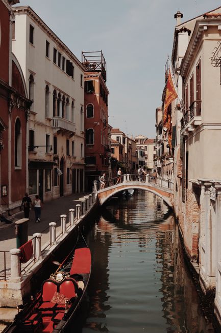 Serene Venetian canal scene featuring a gondola, historic buildings, and a picturesque bridge in Venice, Italy.