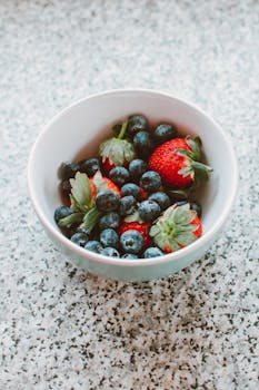 Vibrant strawberries and blueberries in a bowl, perfect for a healthy snack or breakfast option.