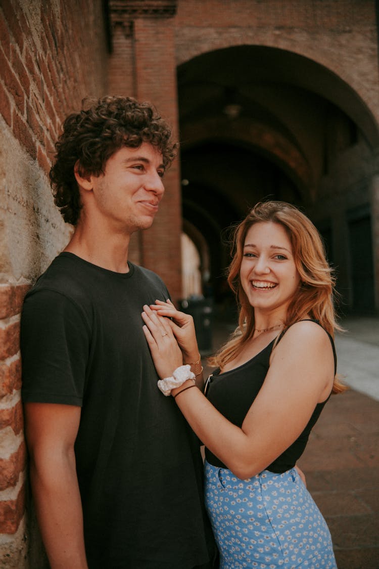 A Young Couple Hugging And Smiling While Standing On The Pavement 