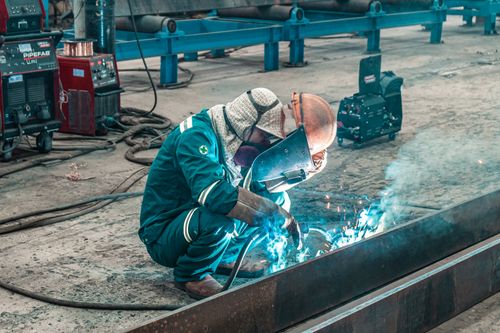 Free A welder using protective gear works on metal in a factory workshop. Stock Photo