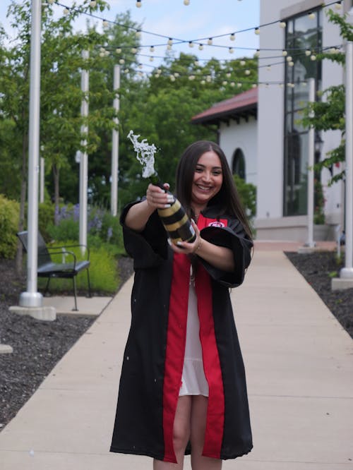 Smiling Graduate Opening Champagne Bottle