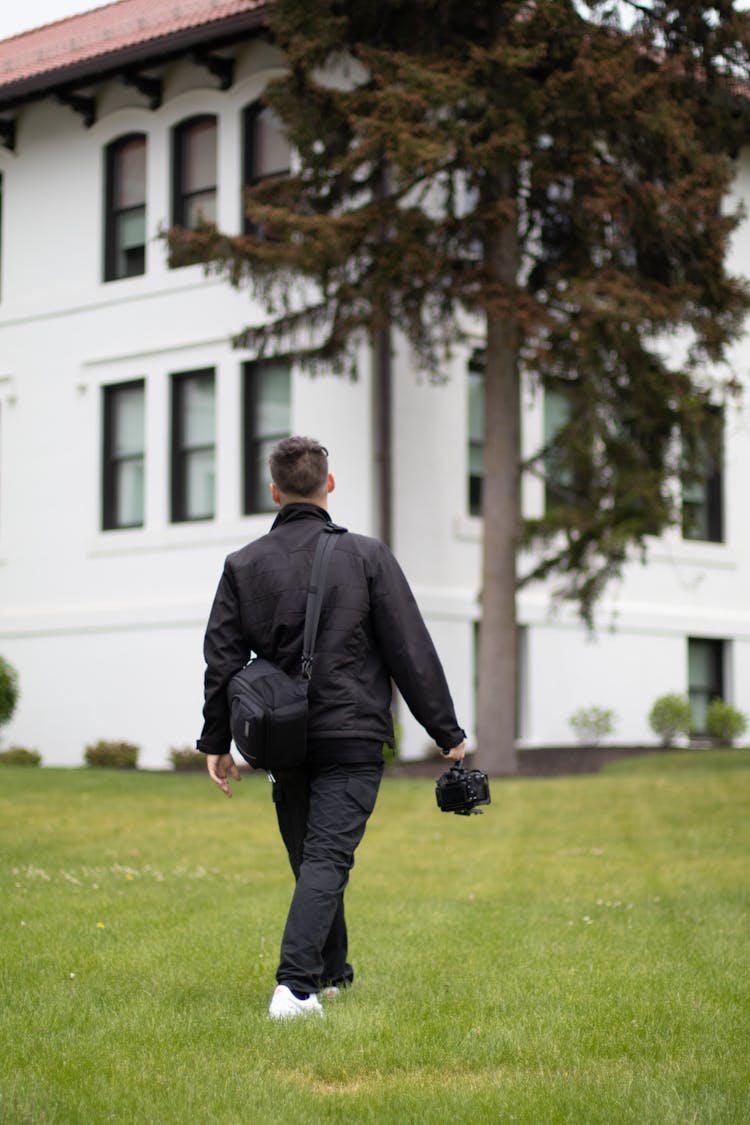 Man In Jacket Walking With Bag And Camera