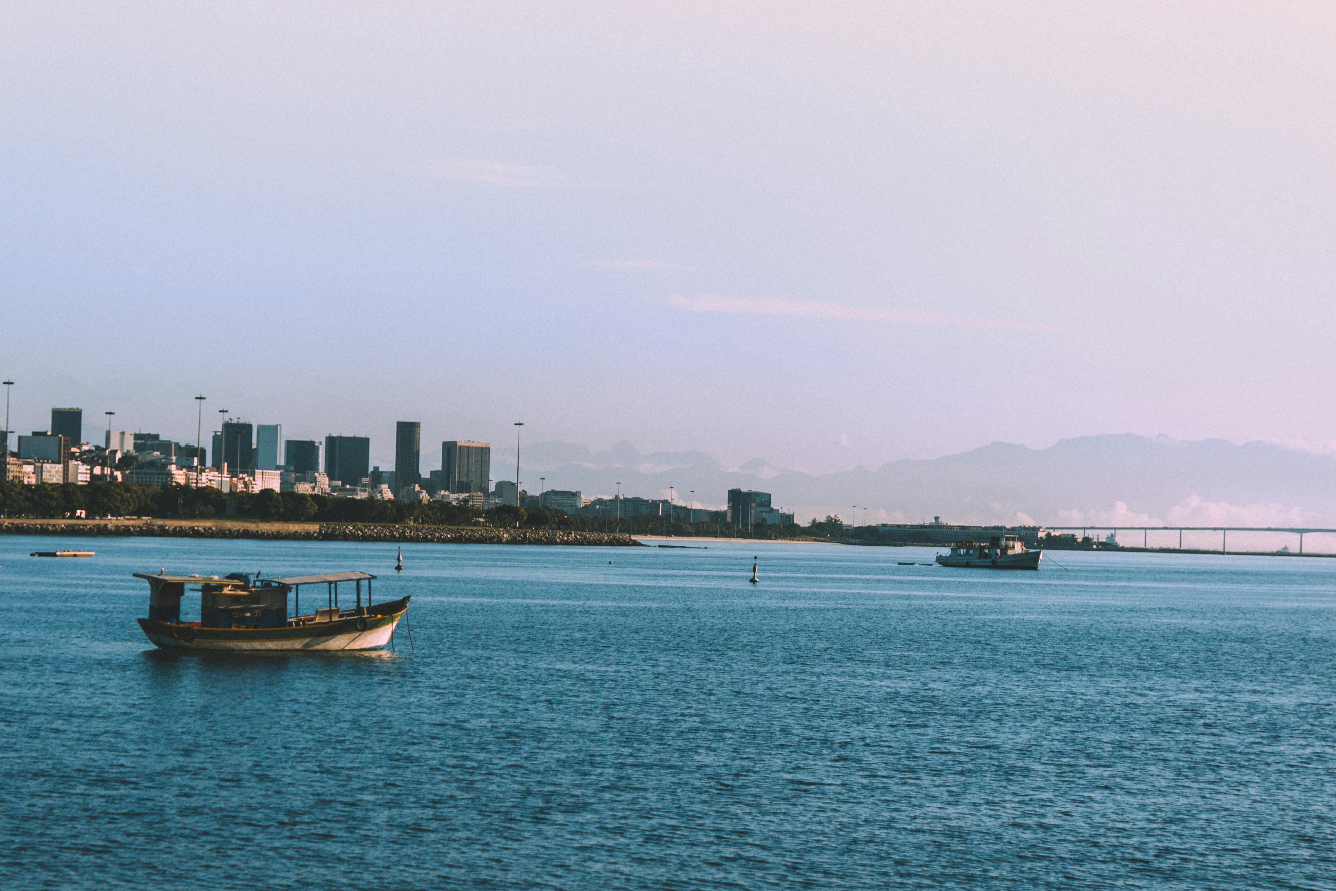 城市天际线和山脉背景下，水面上船只静谧