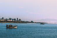 城市天际线和山脉背景下，水面上船只静谧