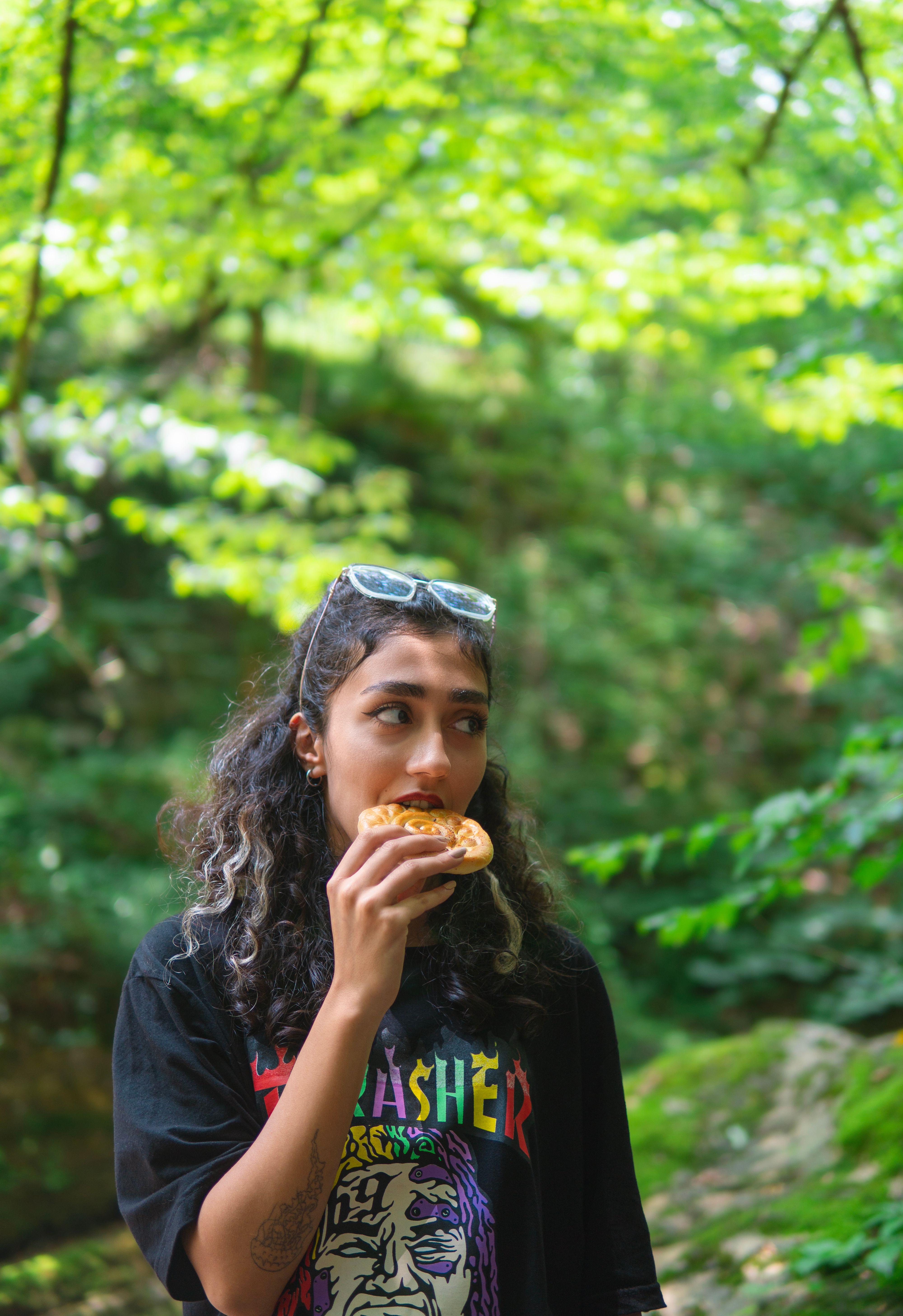 Brunette Woman Eating Food in Forest · Free Stock Photo