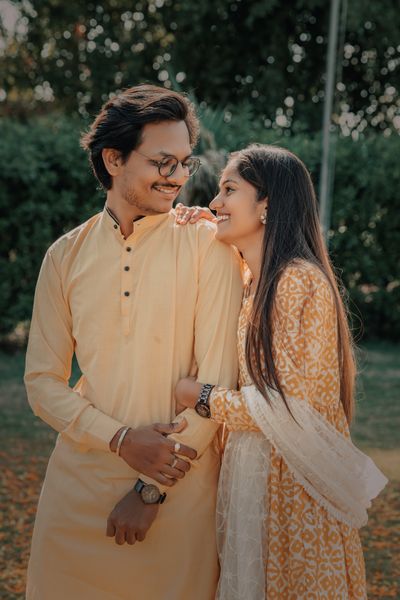 Indian couple in traditional clothing smiling at each other outdoors, expressing joy and affection