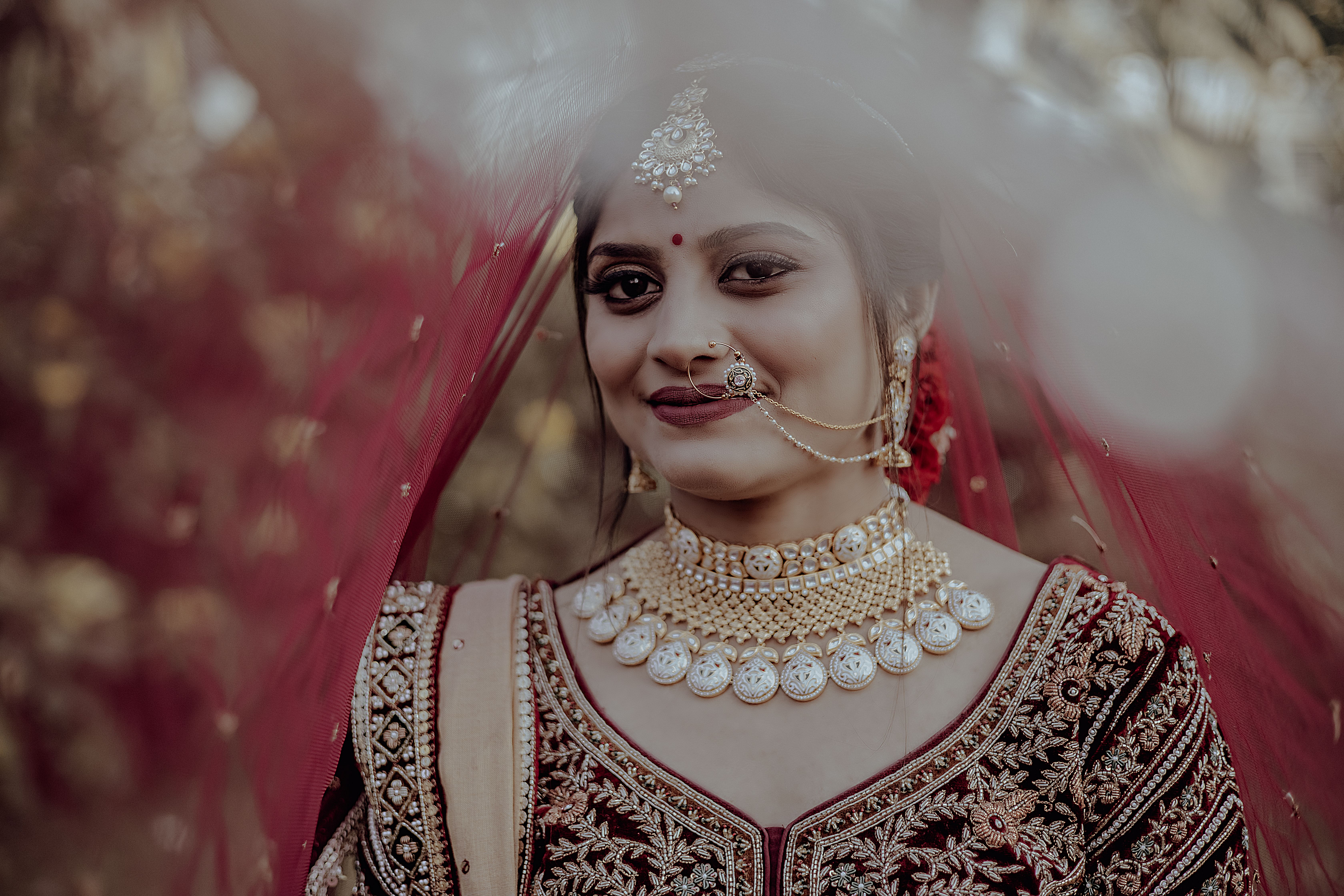Portrait of a smiling Indian bride in ornate jewelry and traditional attire, captured outdoors in Surat, India.
