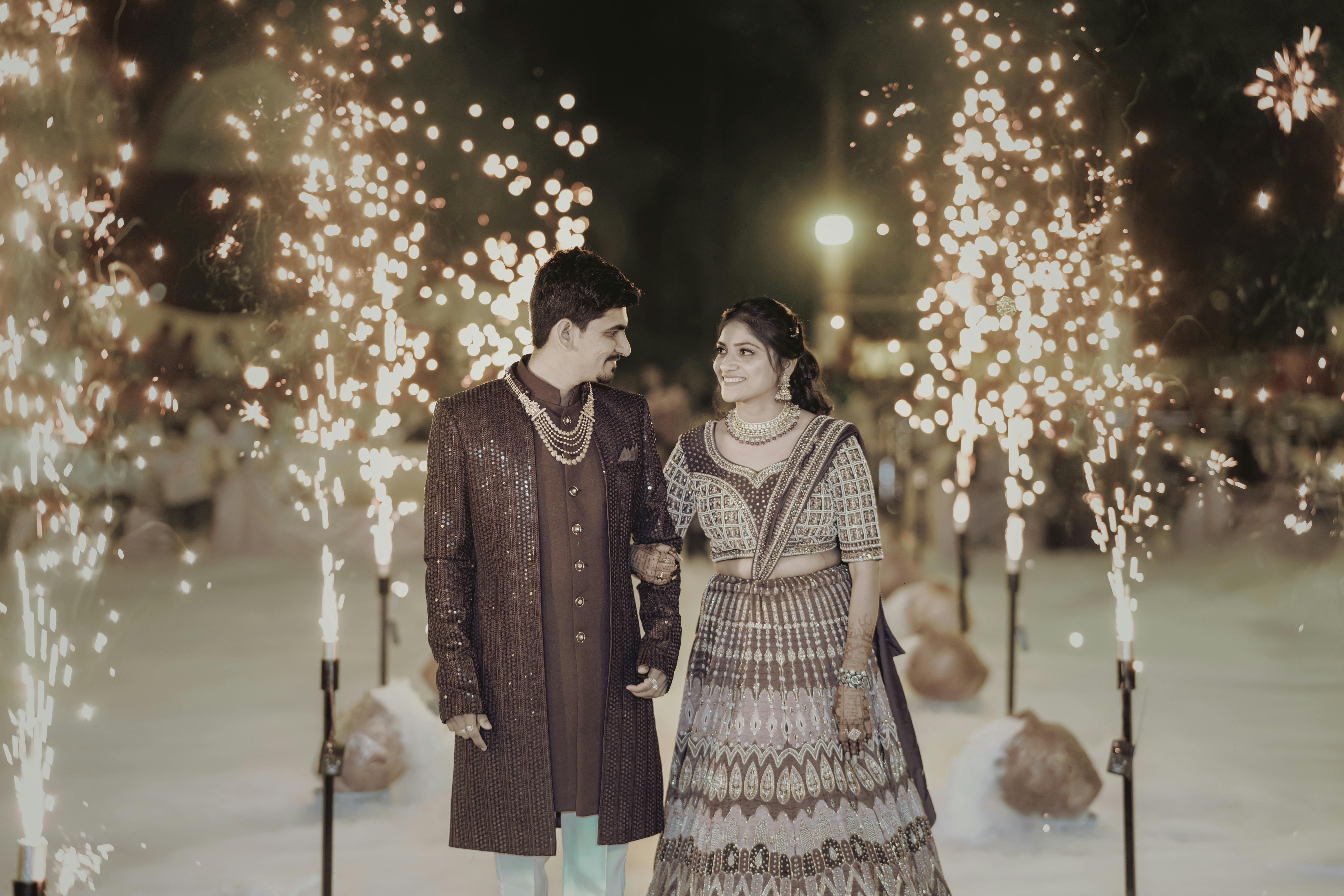Joyful Indian couple celebrating their wedding at night with dazzling fireworks.