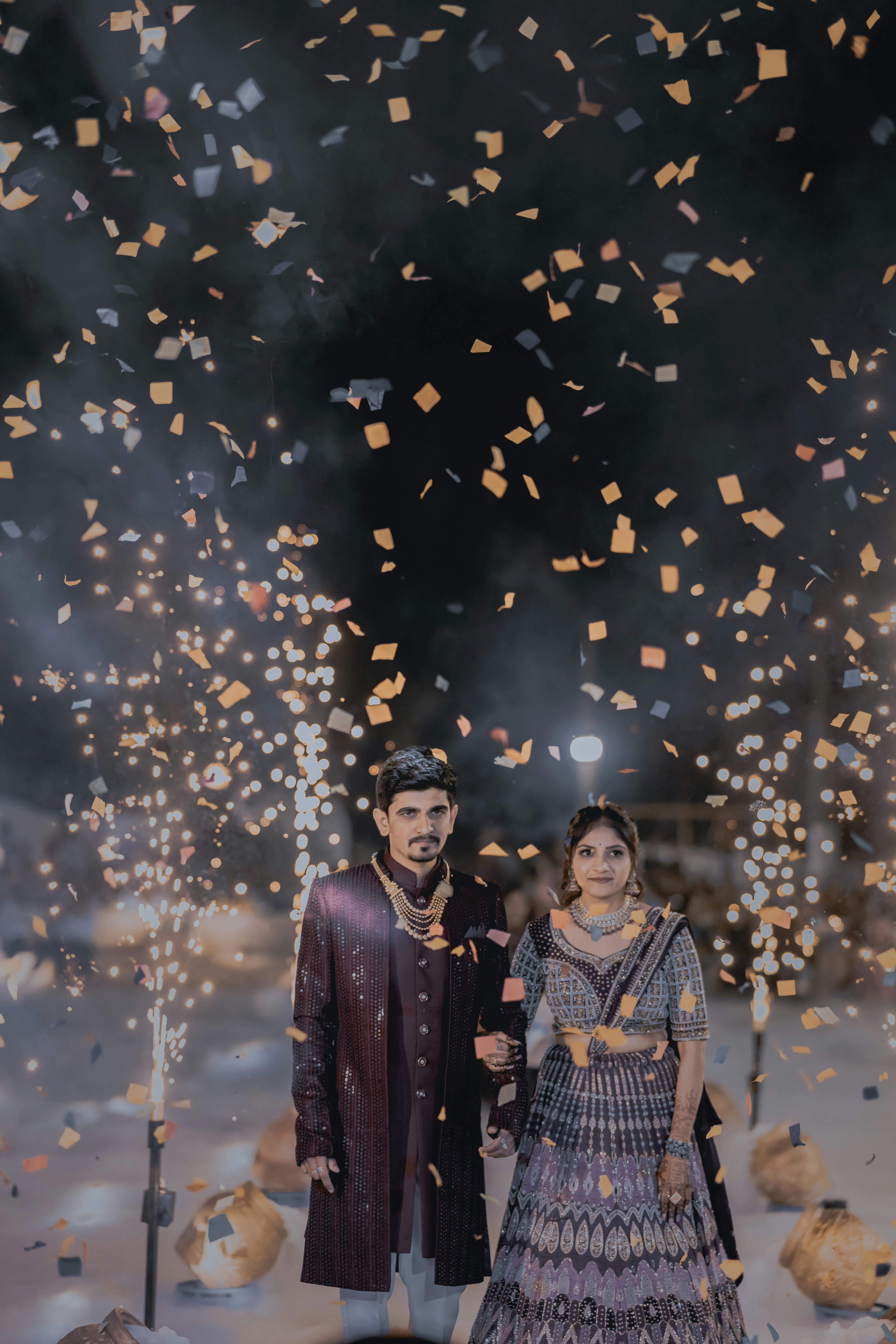 Indian bride and groom enjoying their celebration with confetti and sparklers at night.