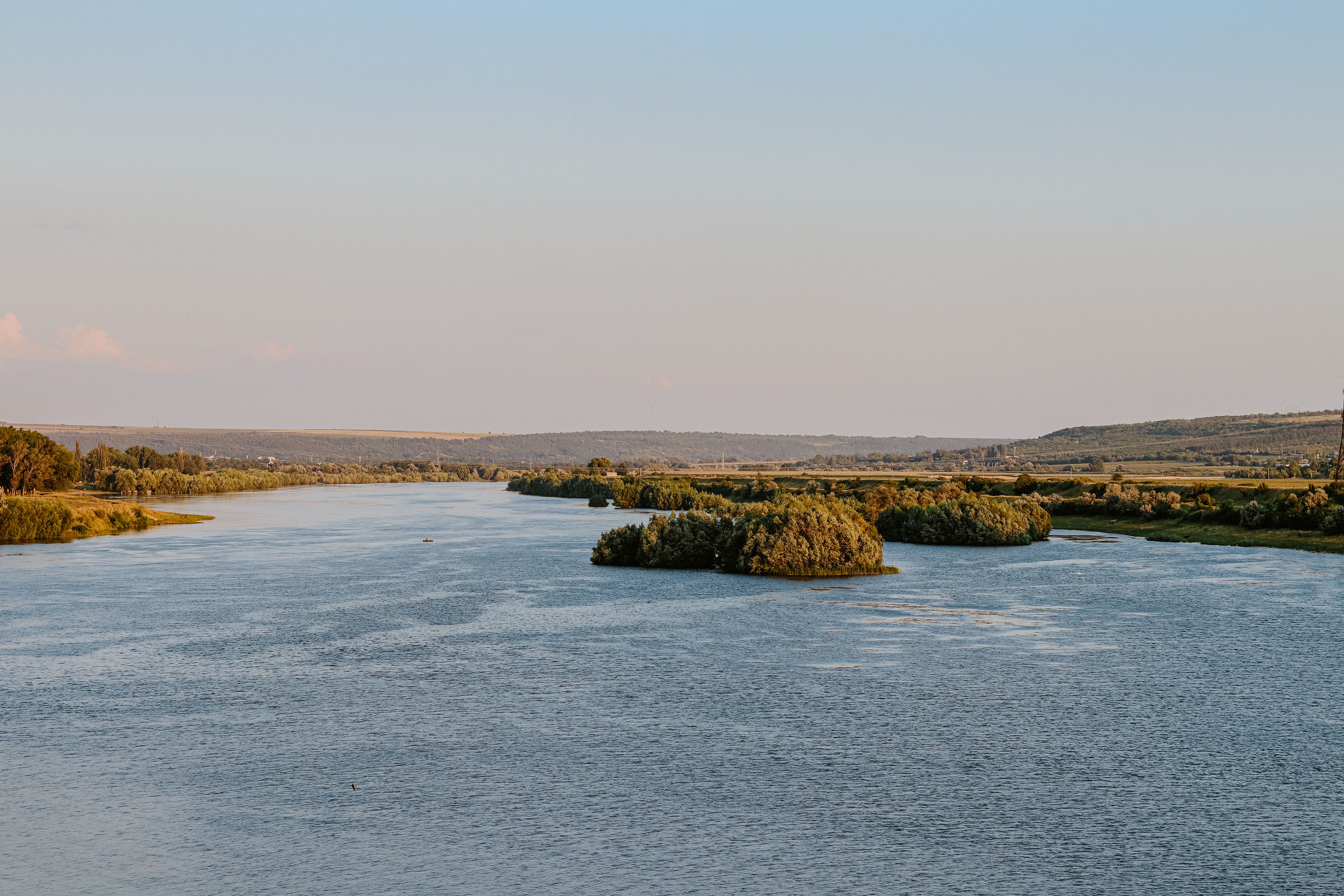 A serene river landscape with lush green islands and a gentle twilight sky.