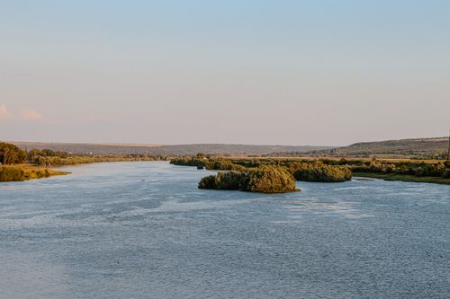 Free A serene river landscape with lush green islands and a gentle twilight sky. Stock Photo