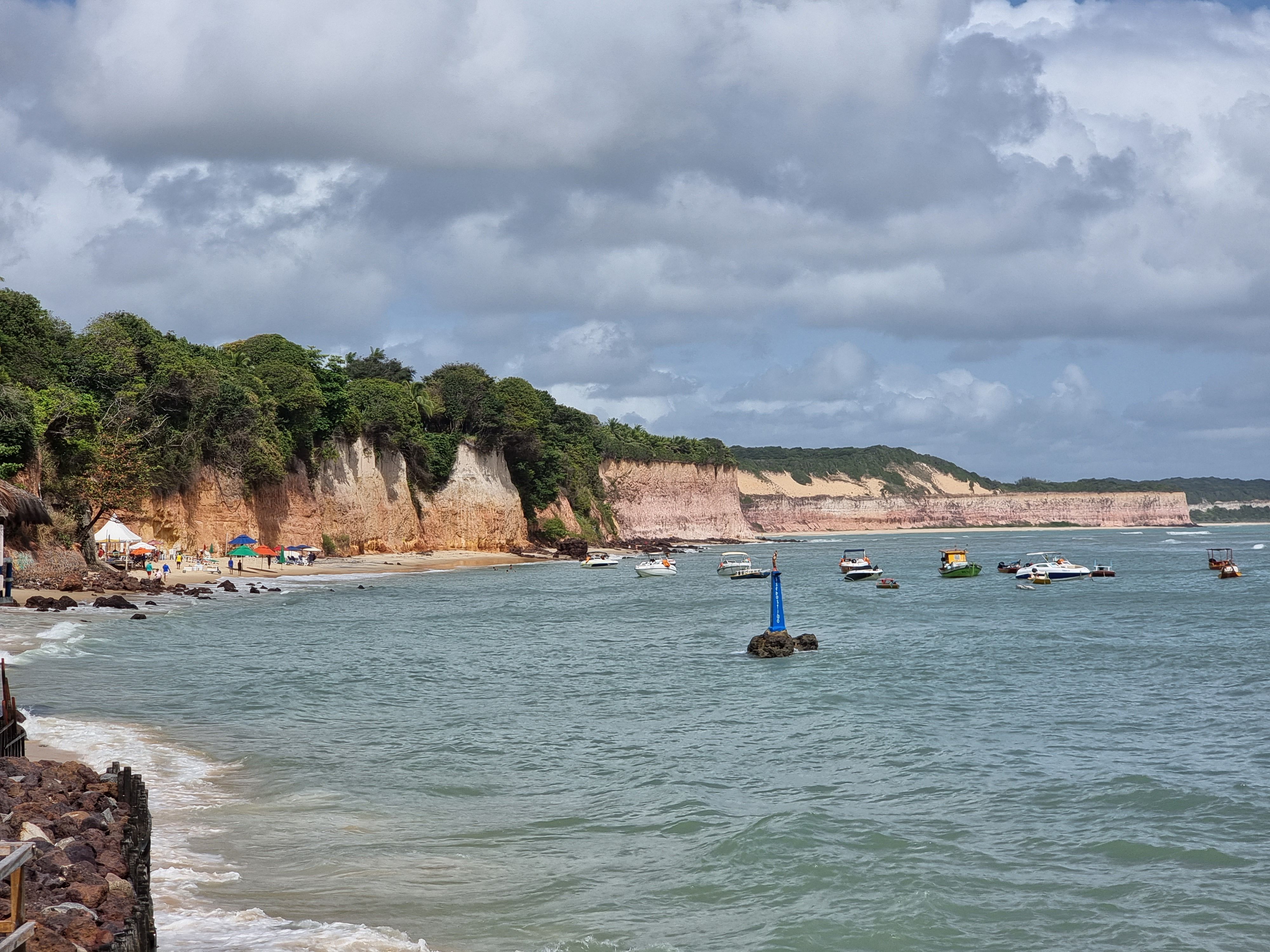 Beautiful coastal scene with cliffs and boats at Pipa beach in Brazil.