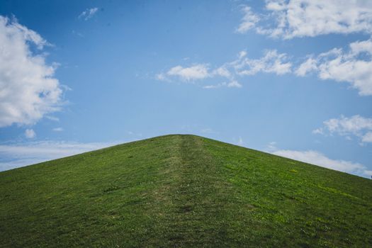 A serene grassy hill under a clear blue sky captures the essence of summer tranquility.