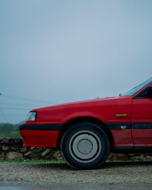 Free Red vintage car positioned outdoors in Salalah, Oman, against a rural backdrop. Stock Photo