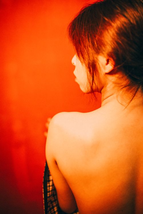 Free Artistic back view of a woman with brown hair against a red backdrop. Stock Photo