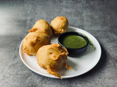 Savor the taste of crispy Indian batata vada served with flavorful green chutney on a plate.