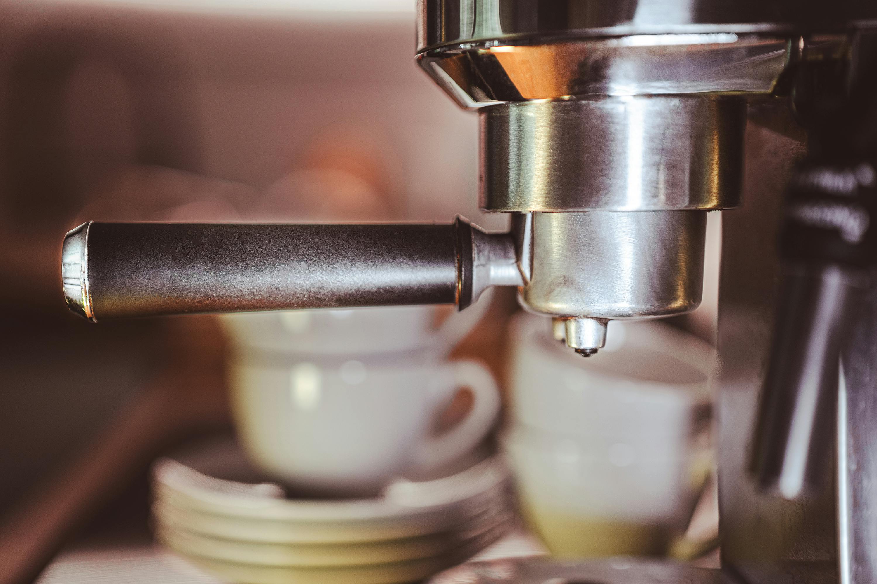 A detailed shot of an espresso machine with cups at a café.