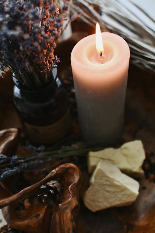 Burning Wax Candle near Flowers in Bottle