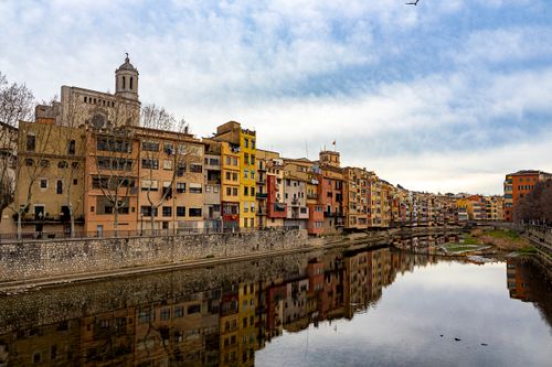 Free Charming view of colorful buildings along the river in Girona, Spain reflecting in the water. Stock Photo