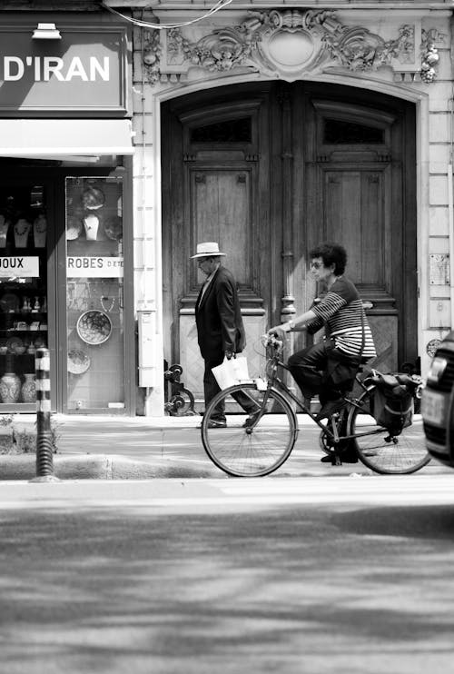 Woman on a Bicycle and Man Walking on the Sidewalk in City 