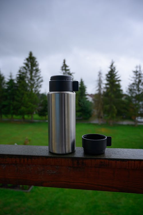 Aluminium Thermos with Hot Drink on Rock Stone Outdoors. Space for