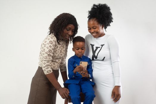 Happy family moment with a child using a smartphone surrounded by loving adults.