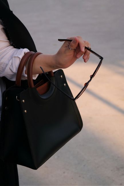 Close-up of a hand holding sunglasses and a stylish handbag in natural light. - Repair Tips for Minor Damages