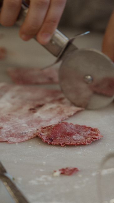 Fotomural Una toma en primer plano de una mano usando un cortador de pizza para preparar masa fresca.