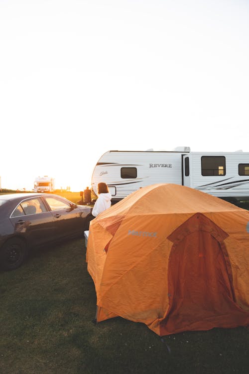 A tent is set up in the grass next to an rv