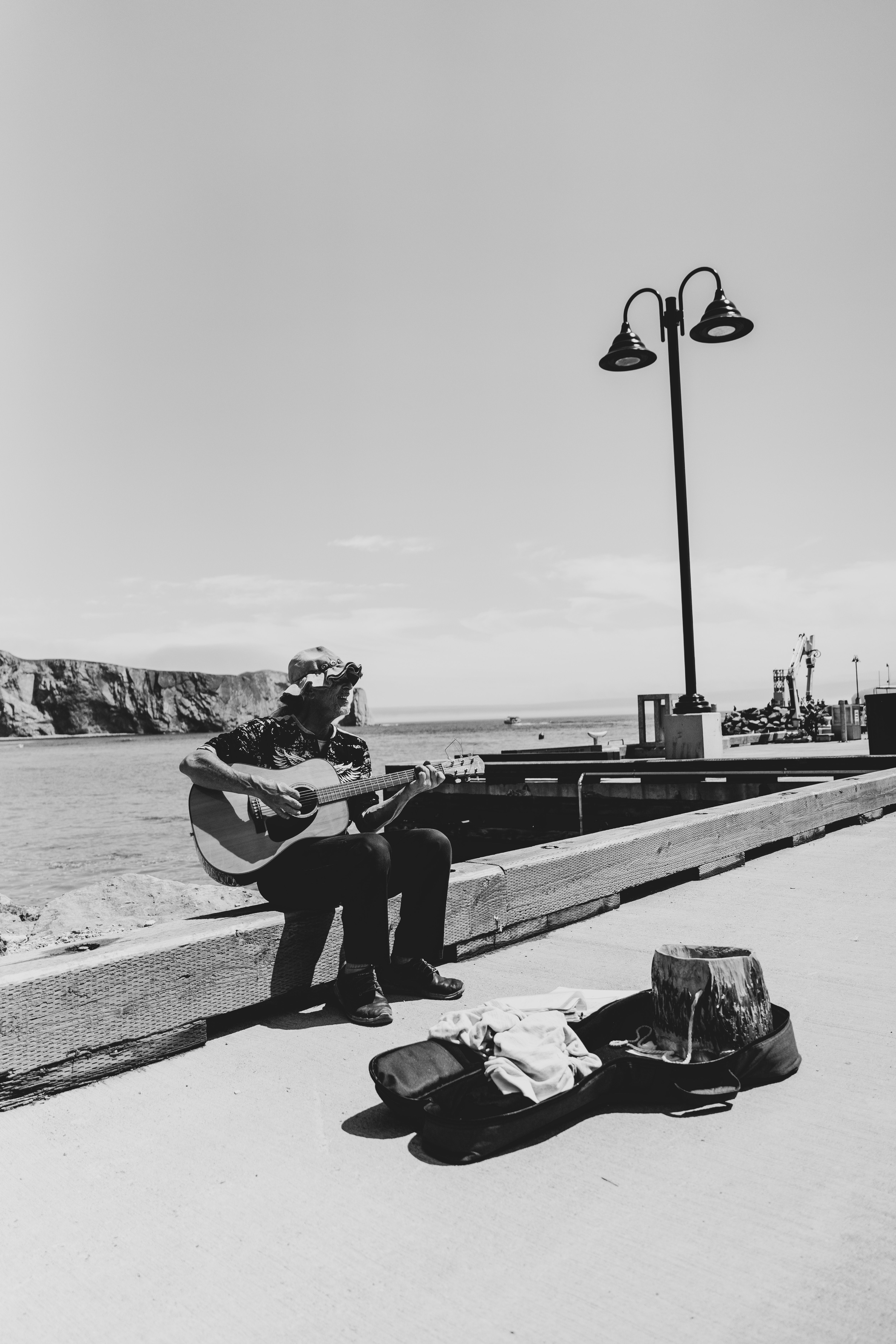 a man sitting on a bench playing guitar near the water
