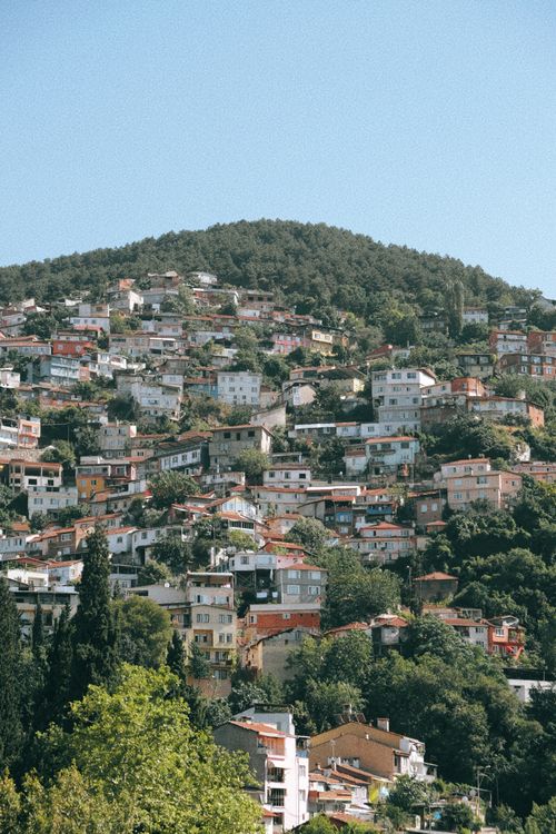 Free A vibrant summer hillside townscape surrounded by lush greenery and clear blue skies. Stock Photo