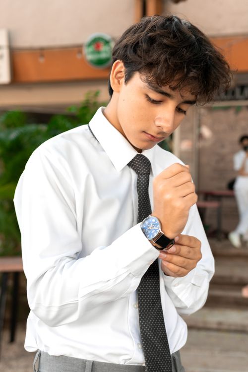 Free Teenager in elegant attire adjusts wristwatch outdoors in Mérida, Mexico. Stock Photo