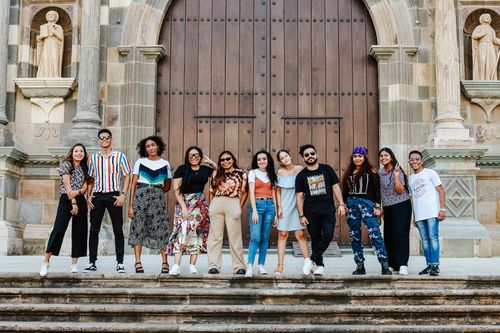 Free A vibrant group of friends posing together at a historic cathedral entrance with large doors and statues. Stock Photo