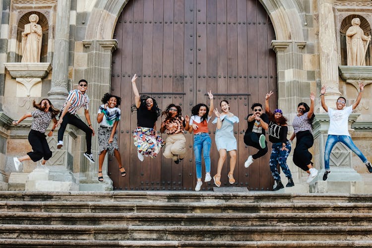 Group Of Young People Jumping In The Air At The Church Steps