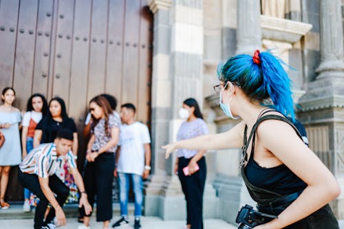 Free Woman with Blue Hair Directing a Photo Shoot of a Group of Young People Stock Photo