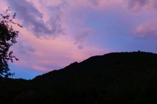 A scenic view of hills in silhouette against a vibrant pink and blue sunset sky.