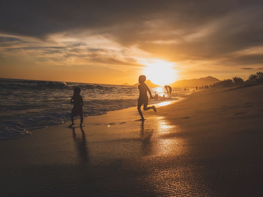 Children playing and swimming in crystal clear tropical beach water with white sand