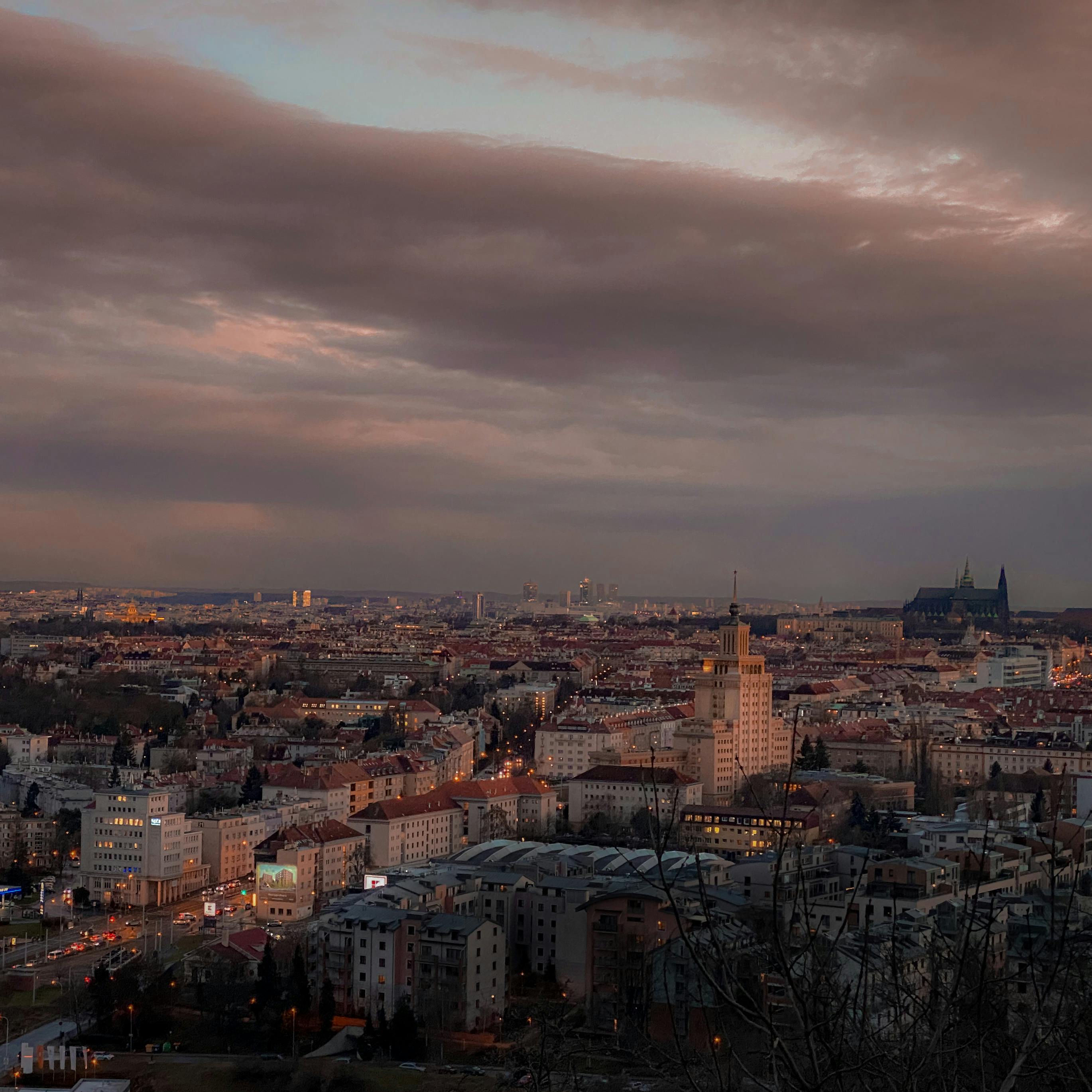 A stunning view of Prague at sunset, showcasing iconic architecture beneath a dramatic sky.