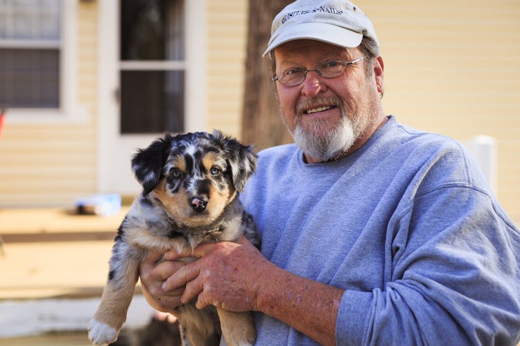 Man Holding Black And Tan Puppy