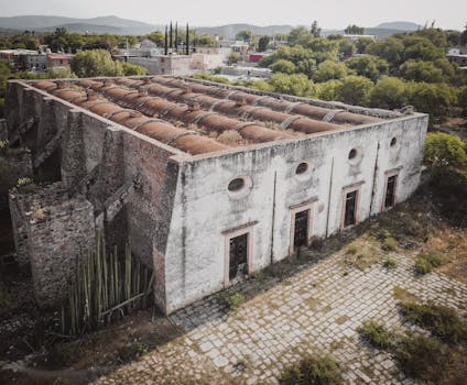 Drone shot of an abandoned historic building in Bocas, S.L.P., surrounded by lush greenery and urban landscape.