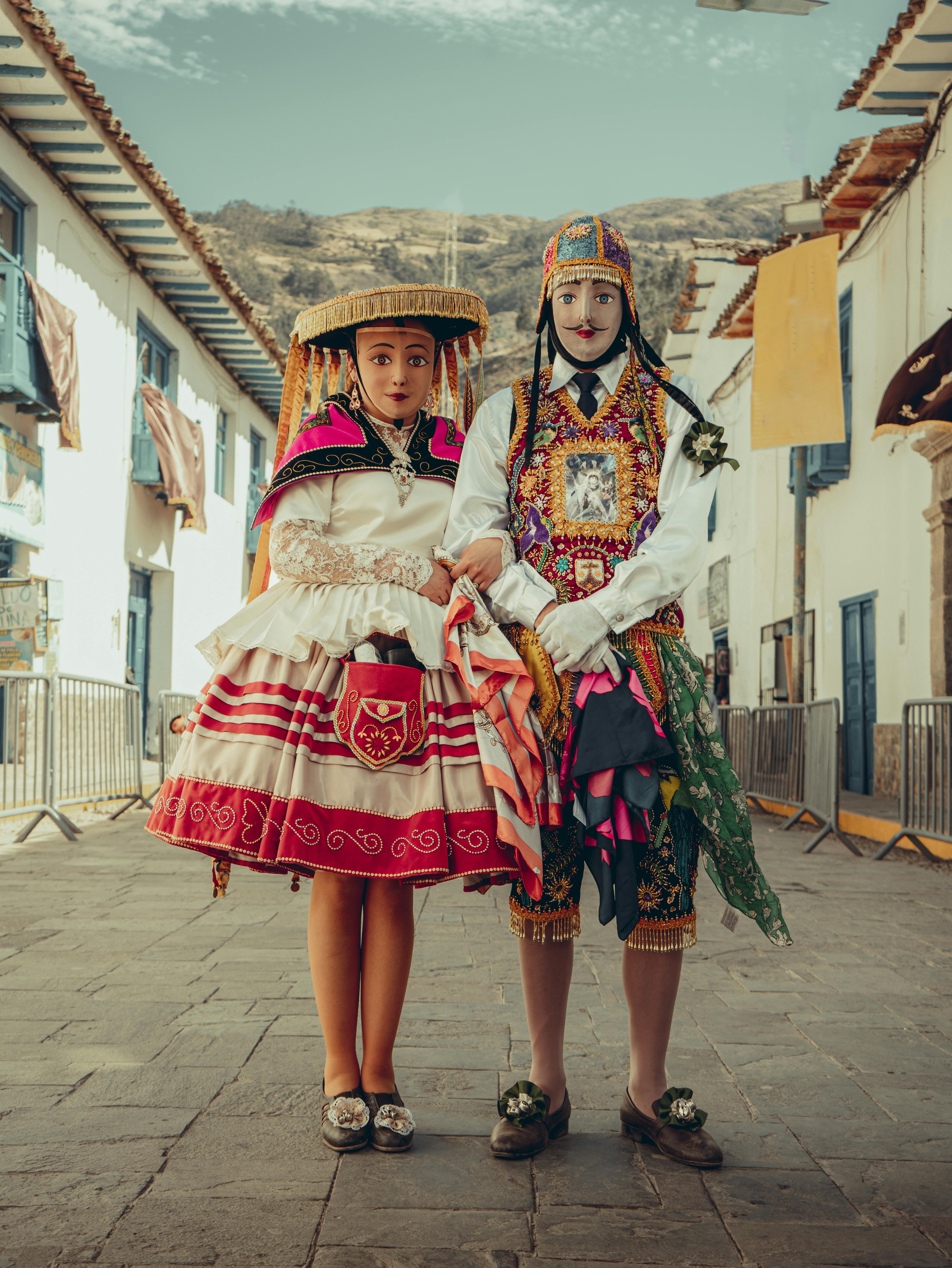 Two individuals wearing intricate traditional Peruvian costumes in a Cusco street.