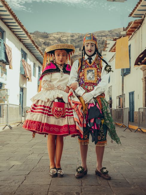 Two individuals wearing intricate traditional Peruvian costumes in a Cusco street.