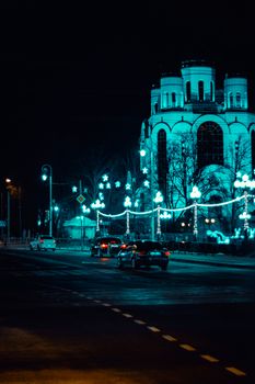 街道夜景中，汽车驶过被灯光照亮的建筑和装饰